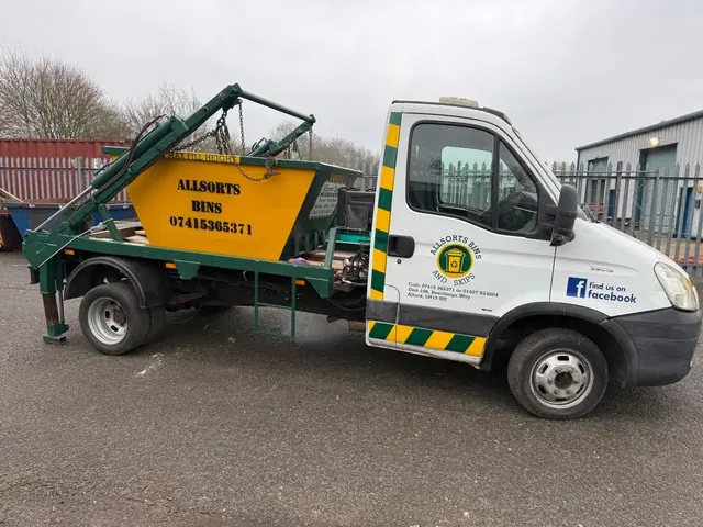Allsorts skip lorry carrying a yellow mini skip